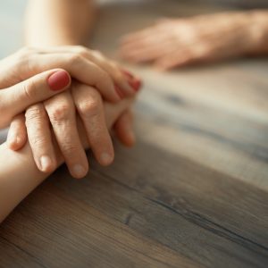 Close up image of younger hands holding older hand.