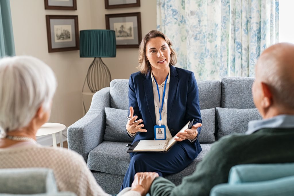 Social worker talking to senior couple in home.