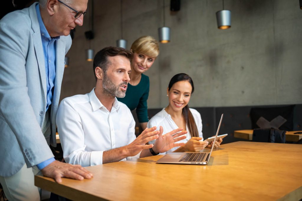 Man in front of laptop talking to staff