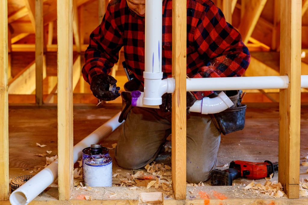 Plumber working on piping in new build