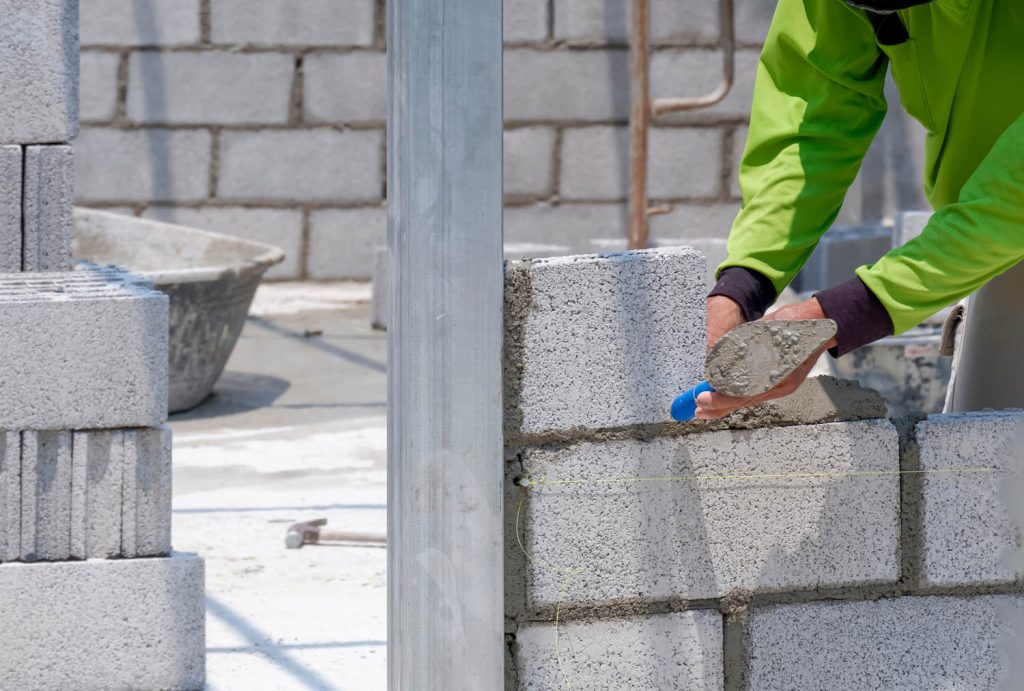 Person using trowel to lay concrete bricks
