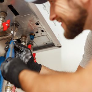 Man fixing underneath of gas boiler