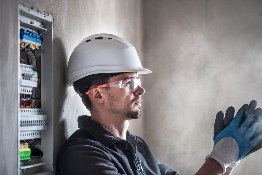 Workman leaning against wall next to fuse box