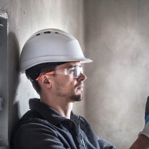 Workman leaning against wall next to fuse box