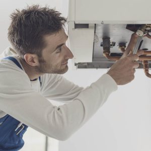 Man fixing underside of gas boiler