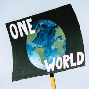 Placard with globe and text: One World