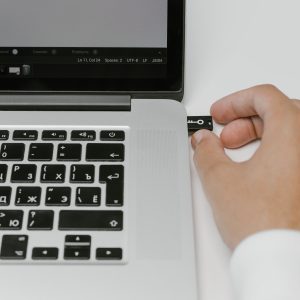 hand plugging in usb with key icon into side of laptop