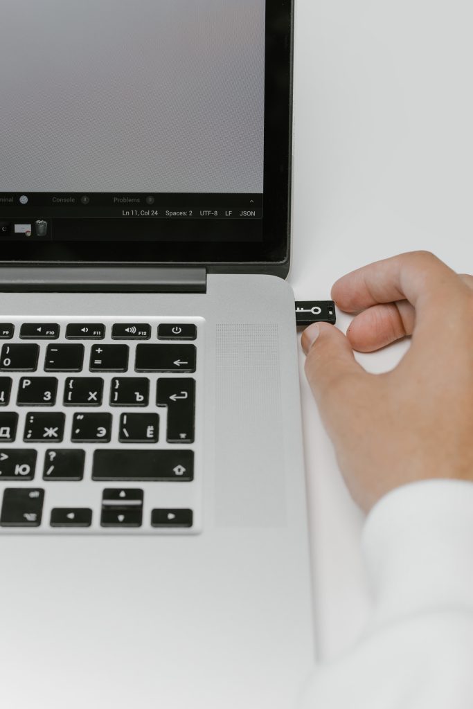 hand plugging in usb with key icon into side of laptop