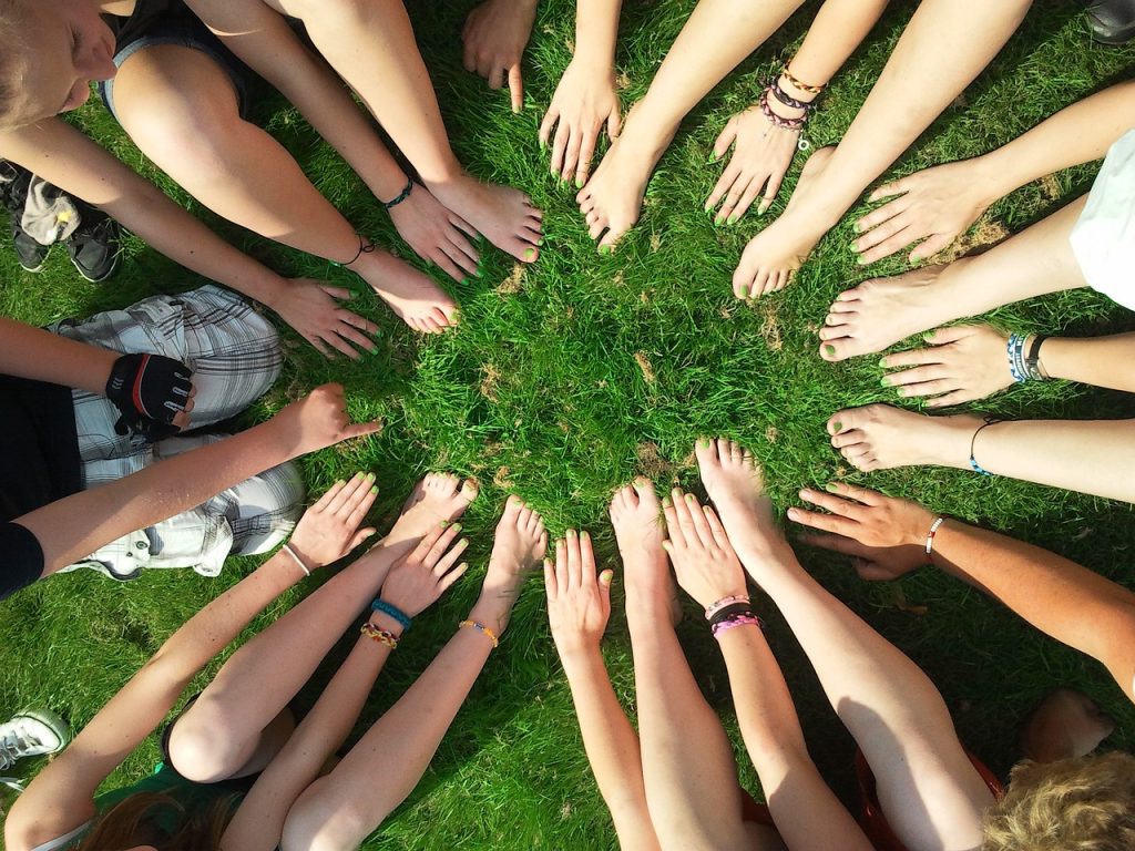 a circle of feet and hands on the grass