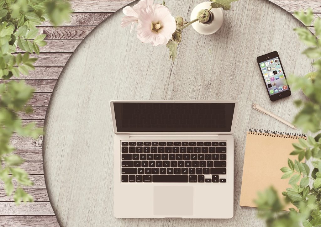 Laptop, phone and notebook on table