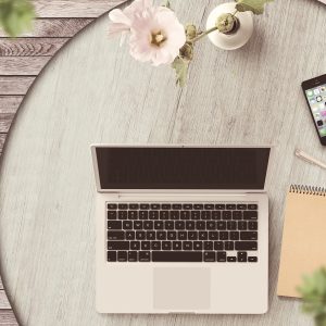 Laptop, phone and notebook on table