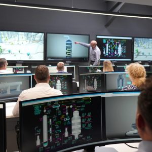 People sitting infant of screens in control room.