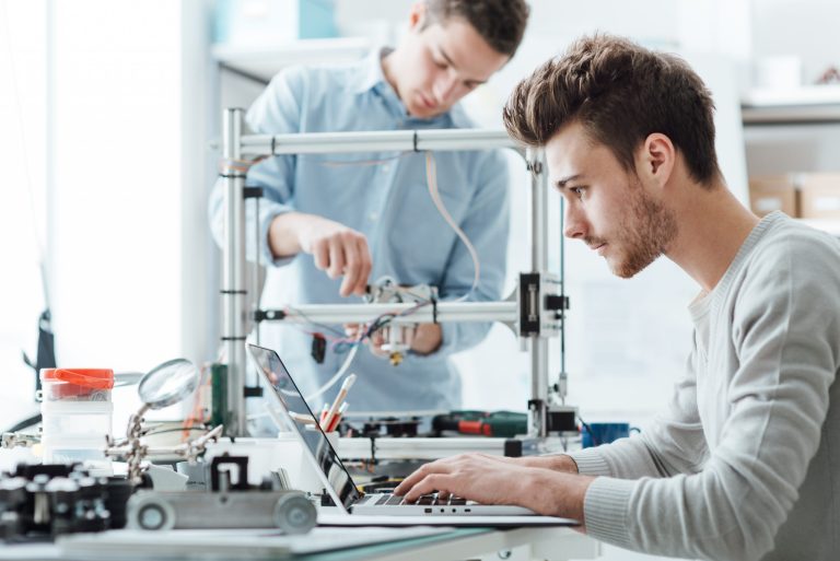 Two people working on electronic machine.