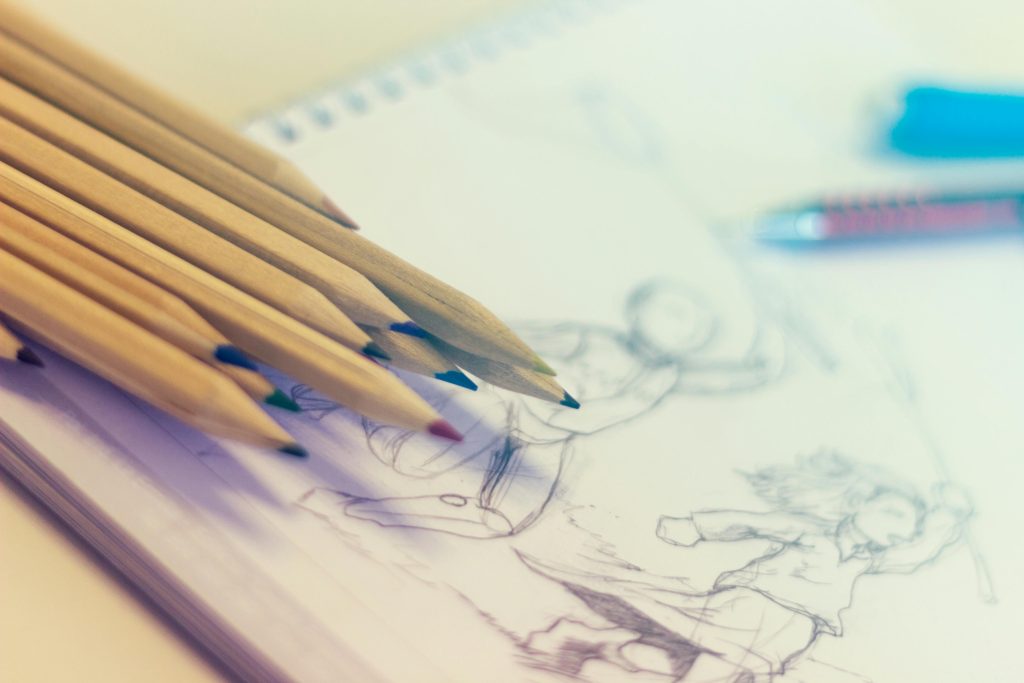 coloured pencils lying on a piece of paper with a drawing on it