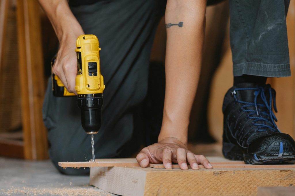 someone kneeling and drilling wood